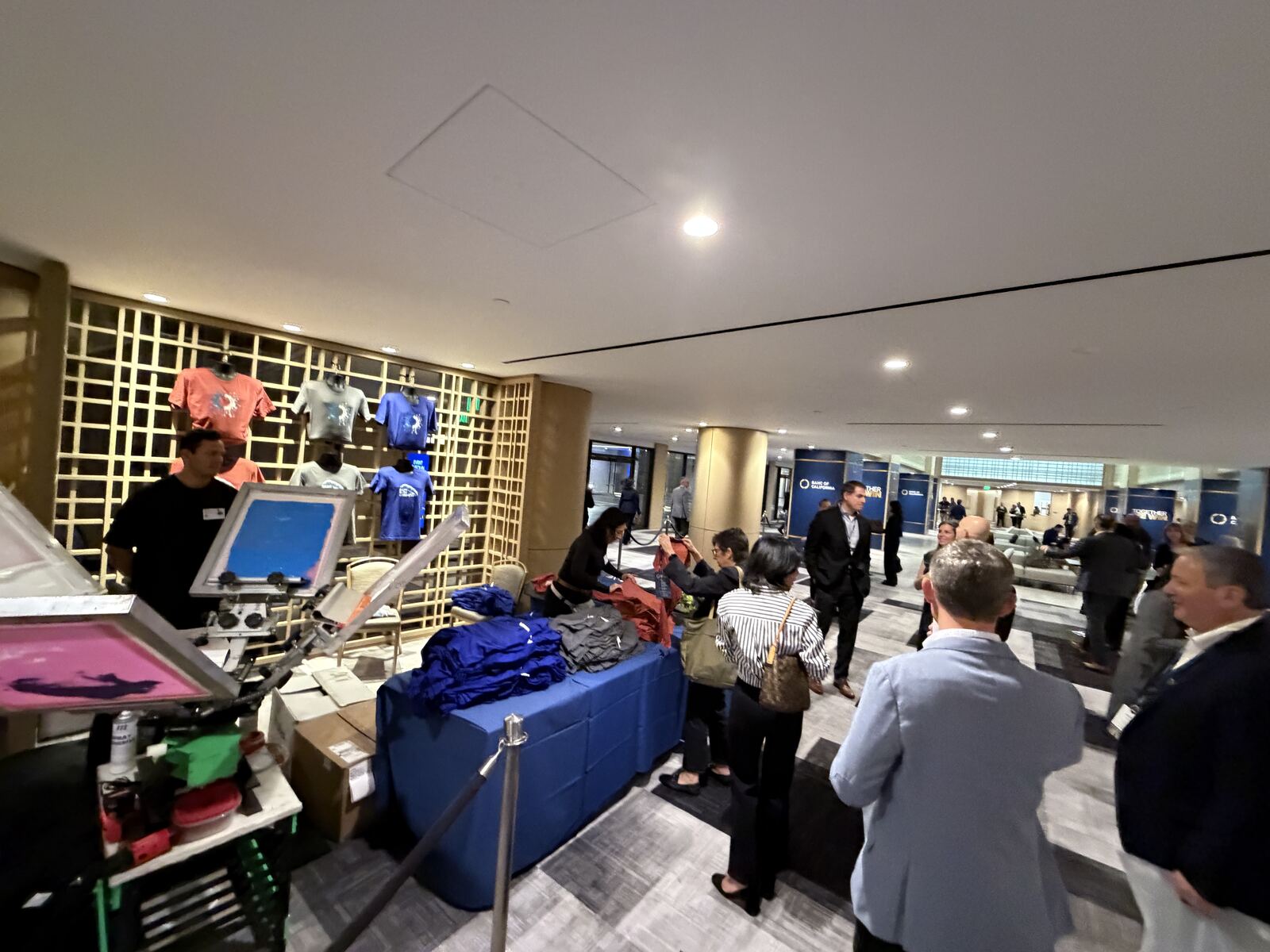 Professional booth interior showing multiple screen printing frames and decorated apparel samples with modern display setup